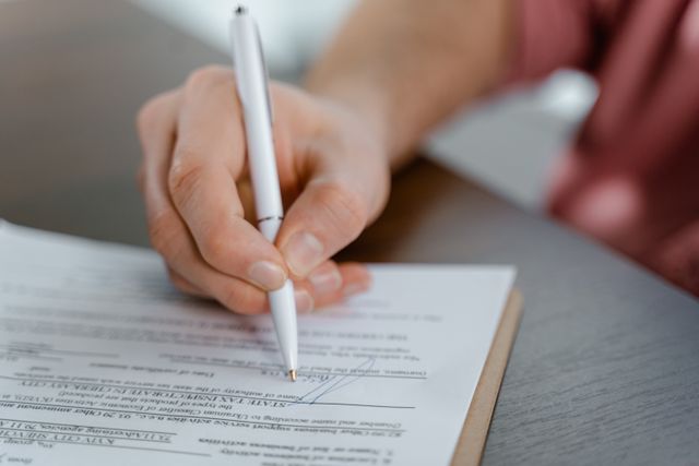 hand signing a document with a pen