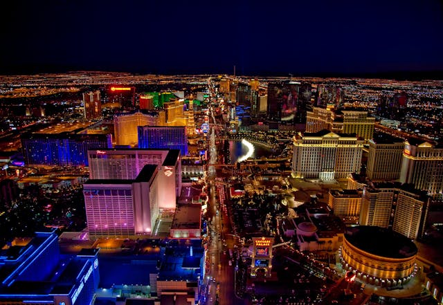 Aerial view of the Las Vegas Strip at night, with brightly lit hotels, casinos, and city lights stretching into the distance.
