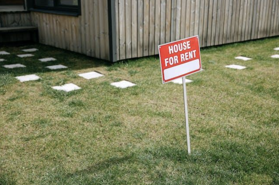 A “house for rent” sign in a yard.